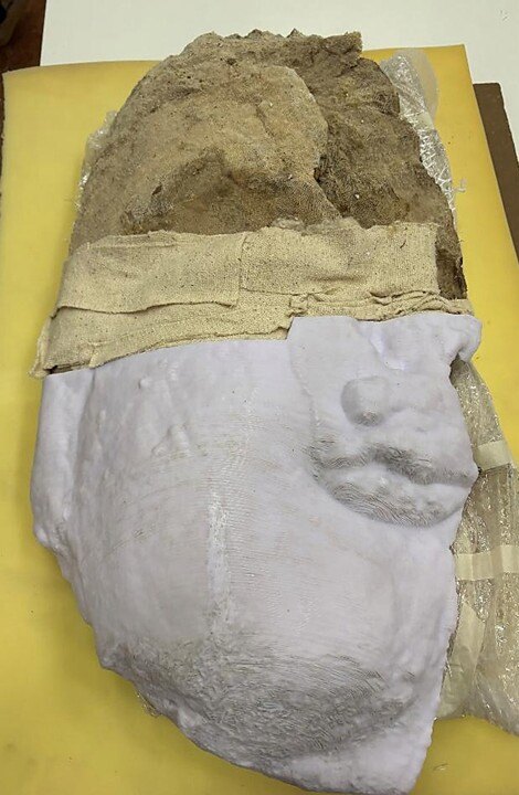 A large artifact, the top half brown stone and the lower half a white shell.