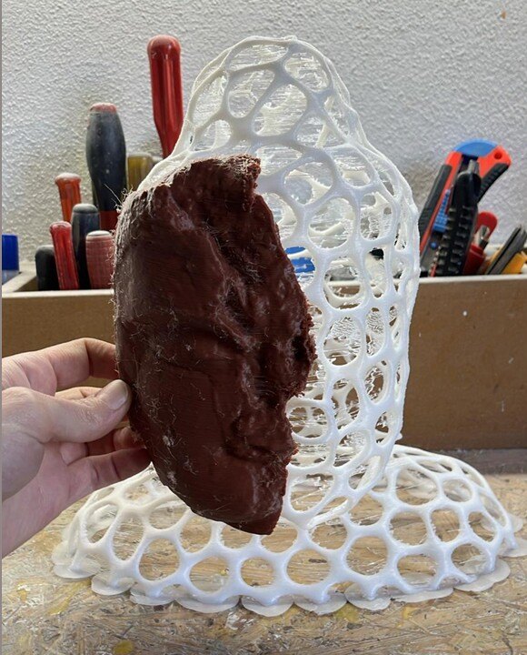 A hand holds a portion of the artifact to compare to a reconstructed sculpture made of connecting circles that form the outline of the artifact.